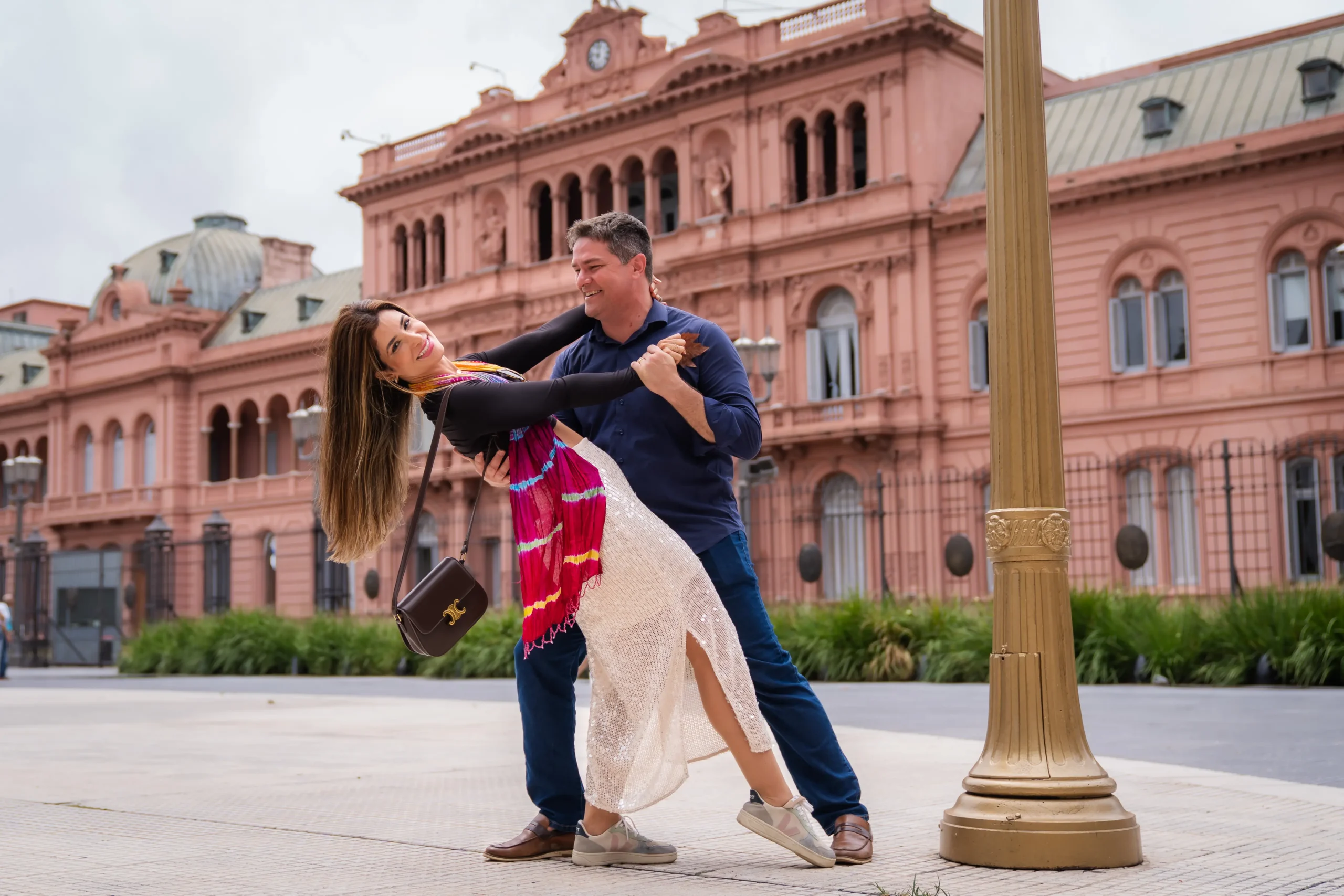 Casal posando para fotos em frente à Casa Rosada, em Buenos Aires.